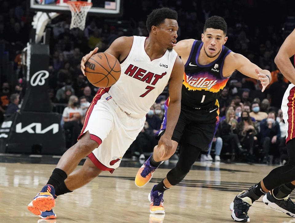 Miami Heat's Kyle Lowry (7) drives past Phoenix Suns' Devin Booker (1) during the first half of an NBA basketball game Saturday, Jan. 8, 2022, in Phoenix. (AP Photo/Darryl Webb)