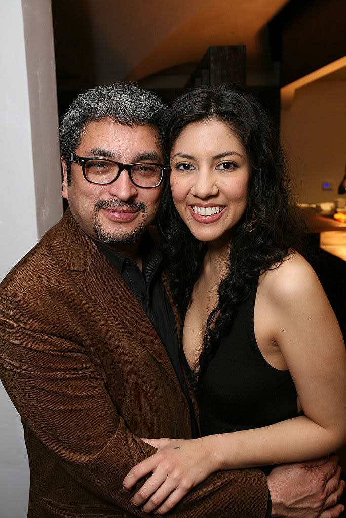 Stephanie Beatriz smiling with her arms around a man