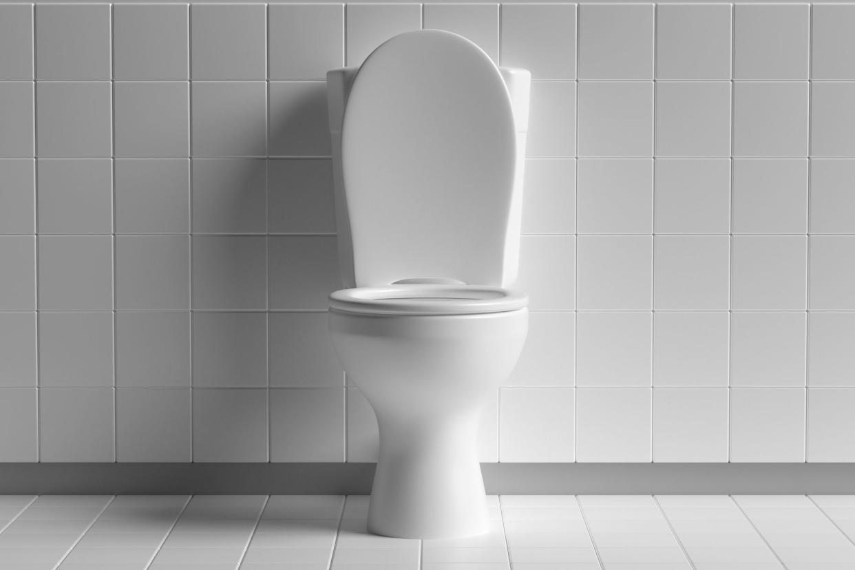 Clean white toilet bowl with white tiled floor and wall