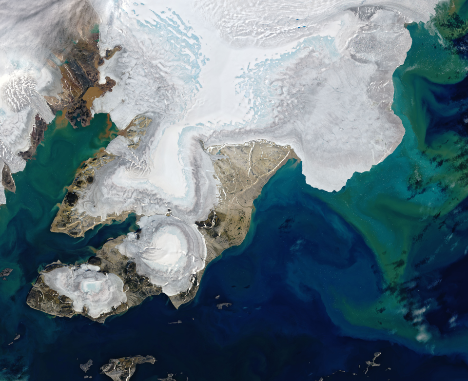 This satellite image of a portion of Nordaustlandet, an island in northeast Svalbard, shows extensive light blue areas where layers of snow have melted away and exposed bare ice, according to NASA. A cluster of small blue dots in the upper right are melt ponds, while colorful water offshore is likely due to sediments eroded by the flow of ice over bedrock and carried by meltwater into the adjacent Arctic Ocean.