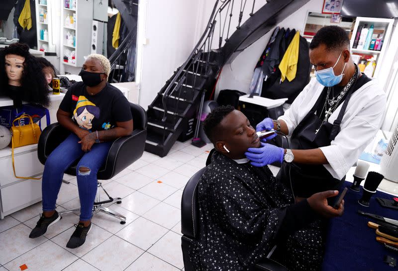 Hairdresser Ambrosio shaves a client in a hair salon of the Matonge gallery in Brussels