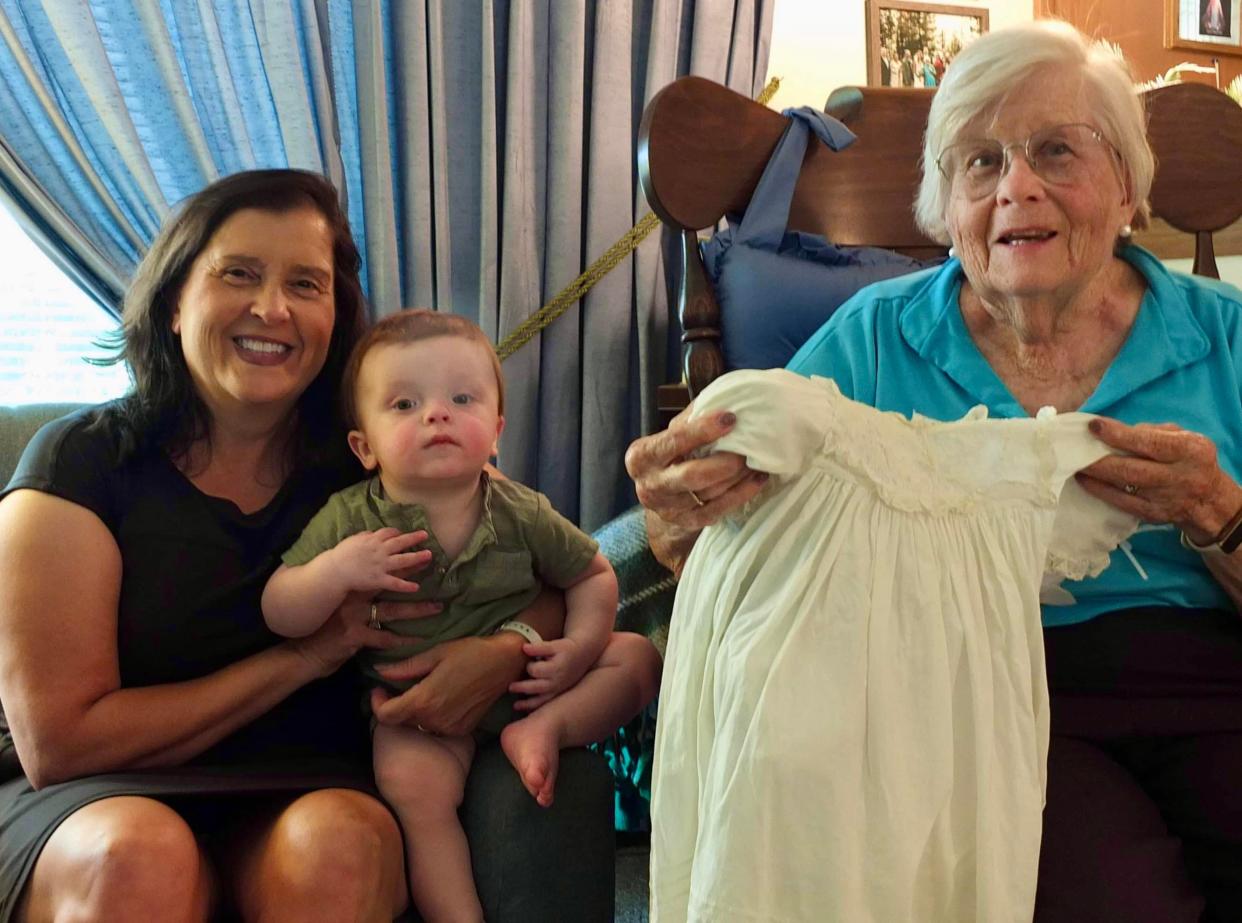 Bernadine (Bernie) Knier (right) holds up a baptismal dress that the family has been using since 1905. Also pictured are Knier's daughter, Mary Howard, and Howard's grandson, Colt Cramer. All three were baptized in the dress.