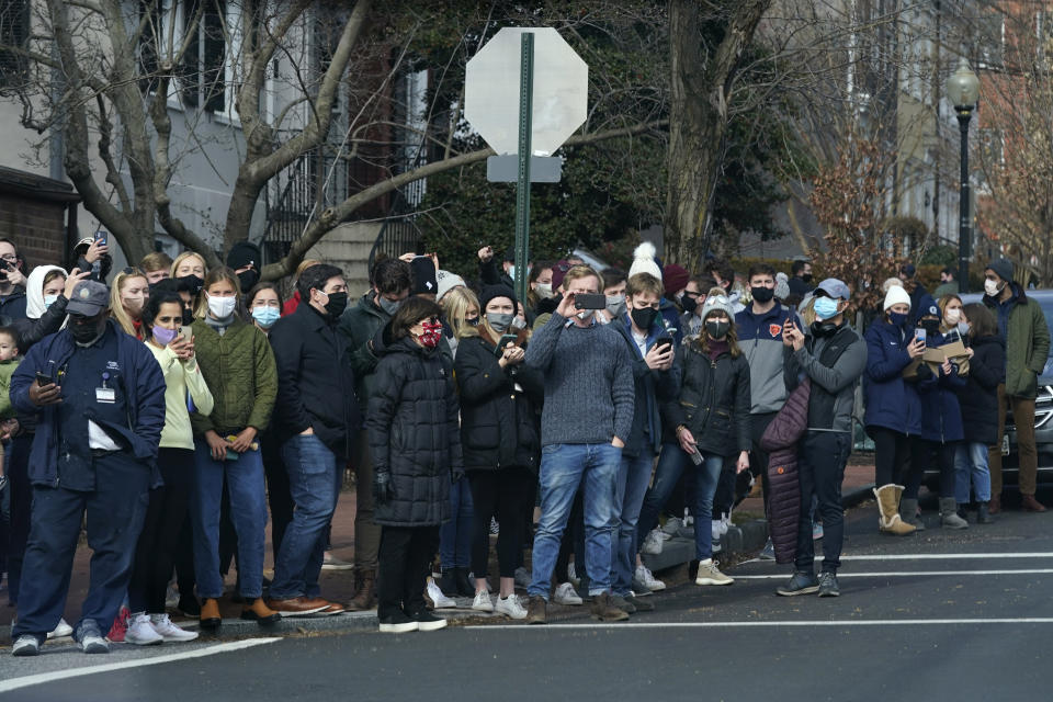 People gather to watch as President Joe Biden's motorcade departs Holy Trinity Catholic Church, Sunday, Jan. 24, 2021, in the Georgetown neighborhood of Washington. (AP Photo/Patrick Semansky)