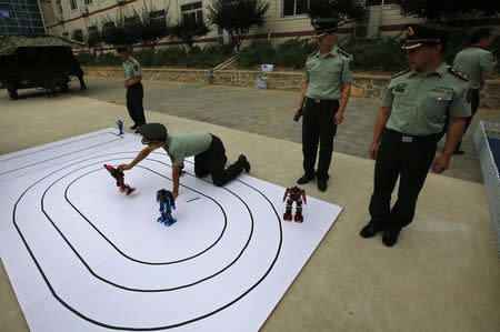 People's Liberation Army (PLA) soldiers demonstrate dancing robots designed by cadets from a PLA engineering school, during an organised media tour at the academy in Beijing July 22, 2014. REUTERS/Petar Kujundzic