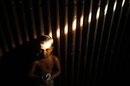 A child looks up while playing in front of a factory made of corrugated iron in Old Dhaka June 4, 2014. REUTERS/Andrew Biraj