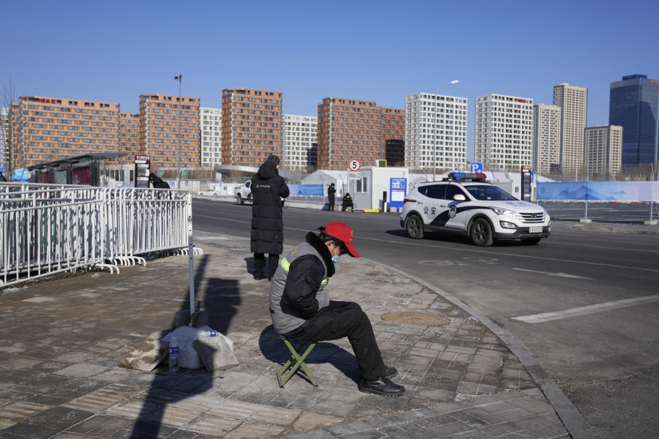 A volunteer sits on duty at a junction into the Winter Olympics Village where athletes are expected to stay in Beijing, China, Tuesday, Jan. 25, 2022. Beijing residents are coping with strict local lockdowns and COVID-19 testing requirements as the Chinese capital seeks to prevent a major coronavirus outbreak ahead of the opening of the Winter Olympics in less than two weeks. (AP Photo/Ng Han Guan)