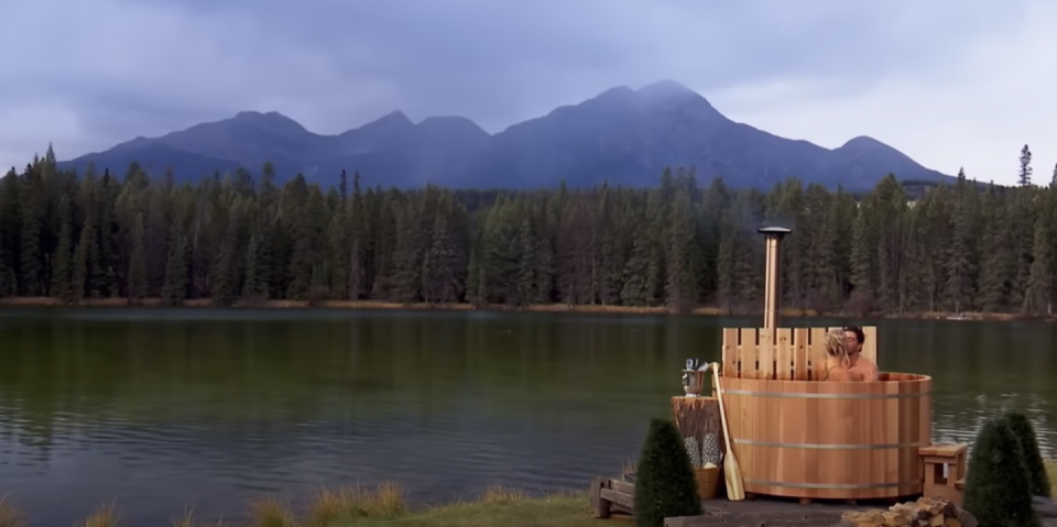 a lake with a dock and a tower with trees and mountains in the background