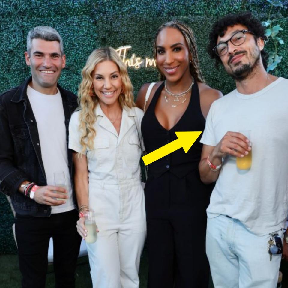 Four people standing together smiling and holding drinks in front of a leafy backdrop. From left to right: Unnamed person, unnamed person, unnamed person, unnamed person