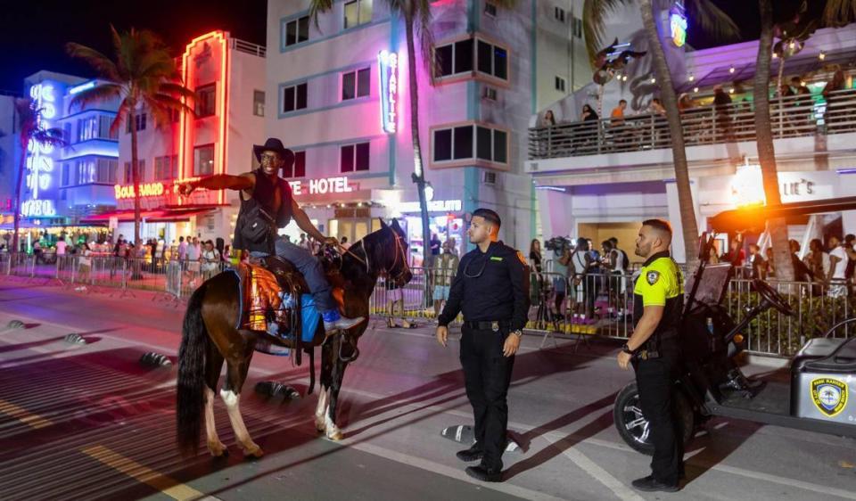 La policía habla con el visitante Stephen Harmon, de Carolina del Sur, mientras monta su caballo Little Bit por Ocean Drive el viernes 8 de marzo de 2024.