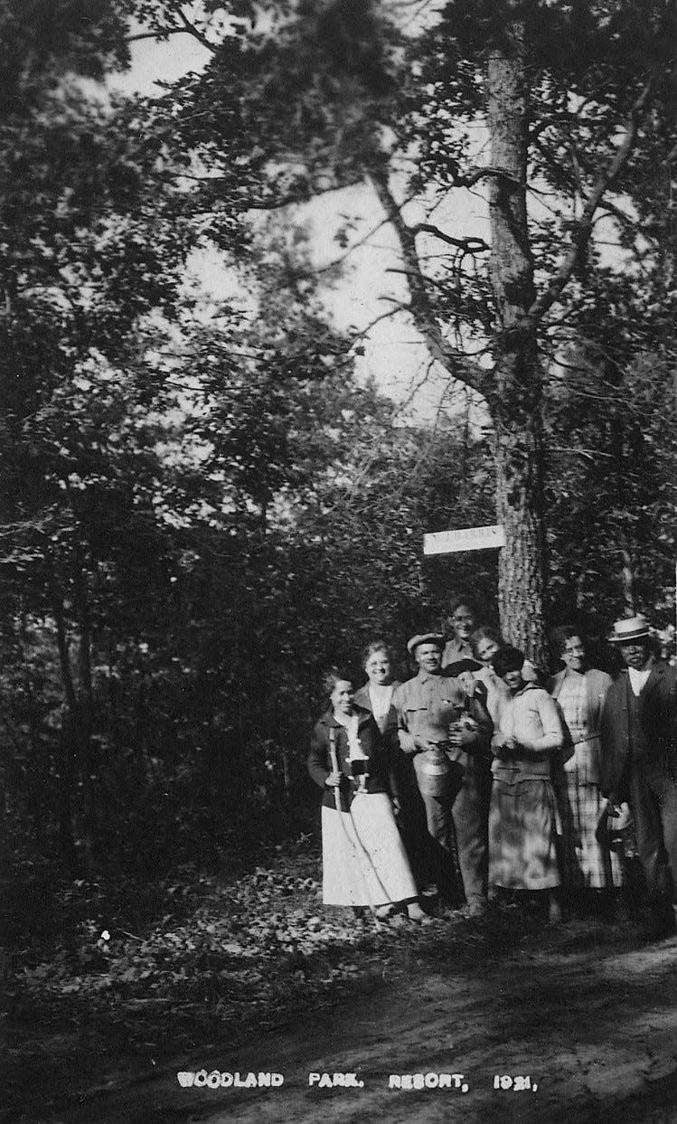 Ella and Marion Auther are shown with other residents and visitors of the Woodland Park resort, circa early 1930s. Ella is holding the stick to the left, and Marion is wearing a hat, two people to the right of Ella.
