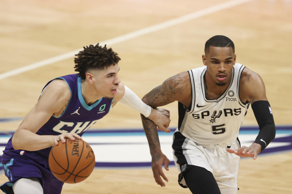 Charlotte Hornets guard LaMelo Ball, left, drives around San Antonio Spurs guard Dejounte Murray (5) during the first half of an NBA basketball game in Charlotte, N.C., Sunday, Feb. 14, 2021. (AP Photo/Nell Redmond)