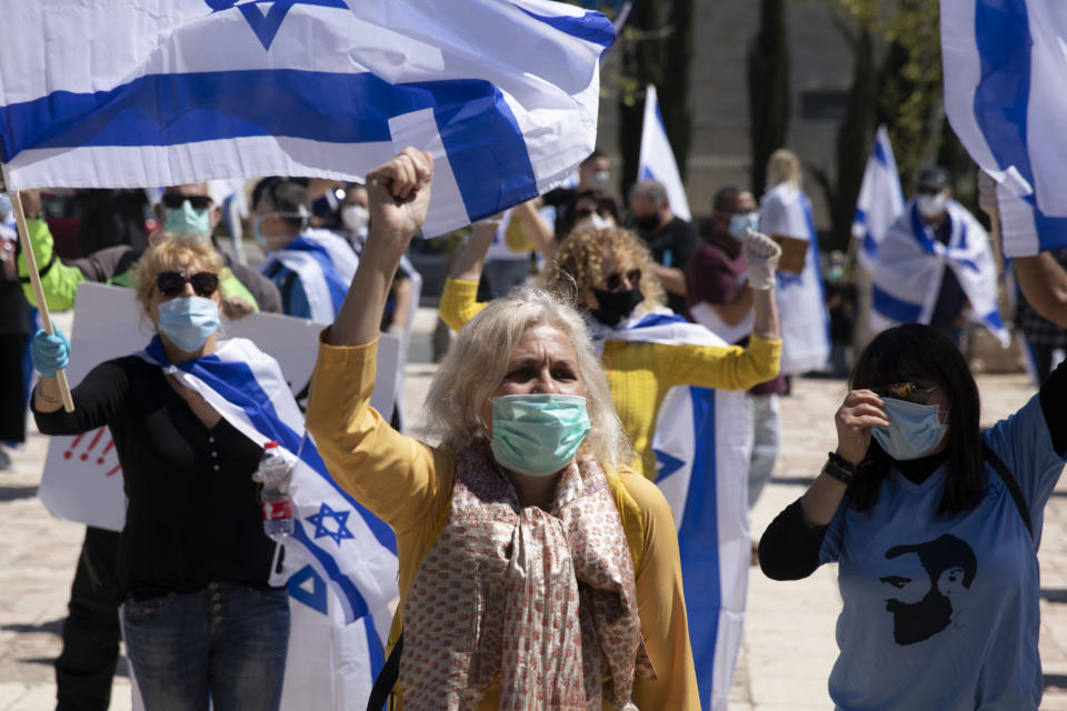 Protesters wearing masks amid concerns over the country's coronavirus outbreak hold Israeli flags and shout slogans during a protest by supporters of Prime Minister Benjamin Netanyahu in front of Israel's Supreme Court in Jerusalem, Thursday, April 30, 2020. Dozens of protesters rallied outside Israel's Supreme Court on Thursday against petitions to disqualify Benjamin Netanyahu from serving as prime minister while facing criminal indictments. (AP Photo/Ariel Schalit)