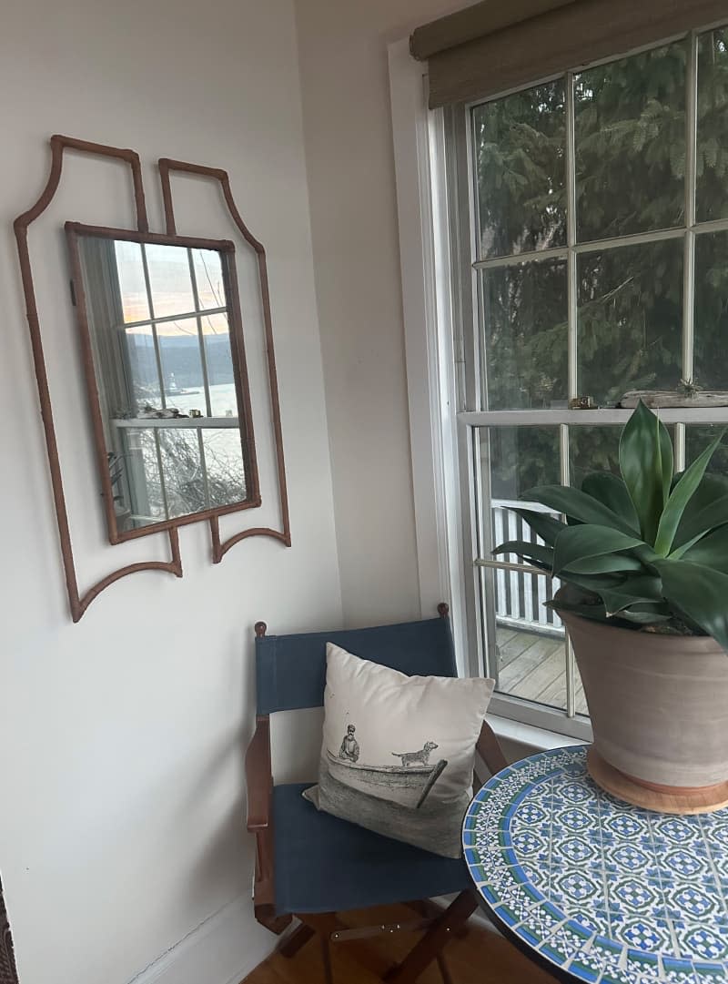 A small dining area with a large window and vintage mirror.