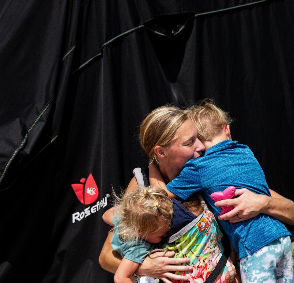 Grace Lipps, 28, hugs her tired and hot children, Salem, 4, Sayler, 22 months, and Saxten, 15 weeks, on July, 24. The family lives in an RV on San Carlos Island on Fort Myers Beach. They are helping family members recover from Hurricane Ian while also working on their home that was damaged.