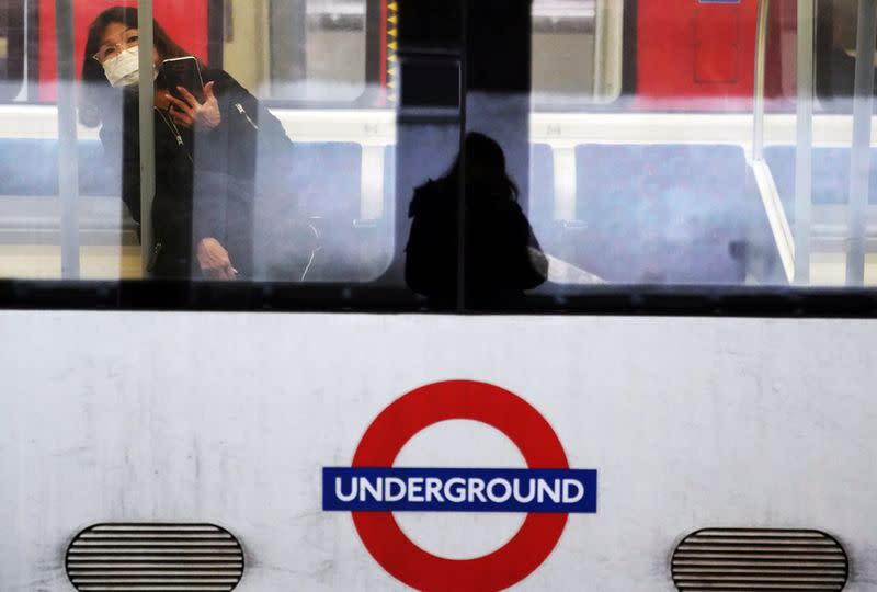 A woman wearing a protective mask travels on a Jubilee Line tube train in London