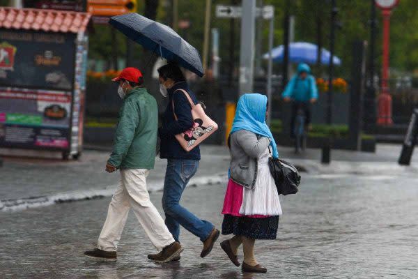 personas caminan bajo la lluvia durante una tormenta tropical