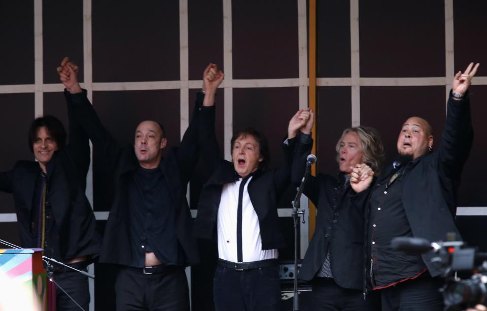 Paul McCartney raises arms with members of band after playing surprise mini-concert in New York's Times Square