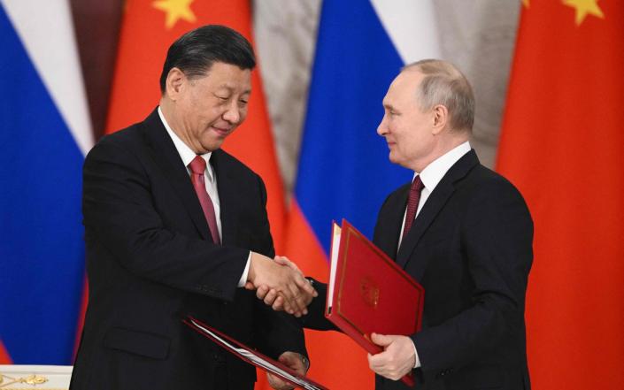 Russian President Vladimir Putin and China's President Xi Jinping shake hands at the Kremlin - VLADIMIR ASTAPKOVICH/AFP