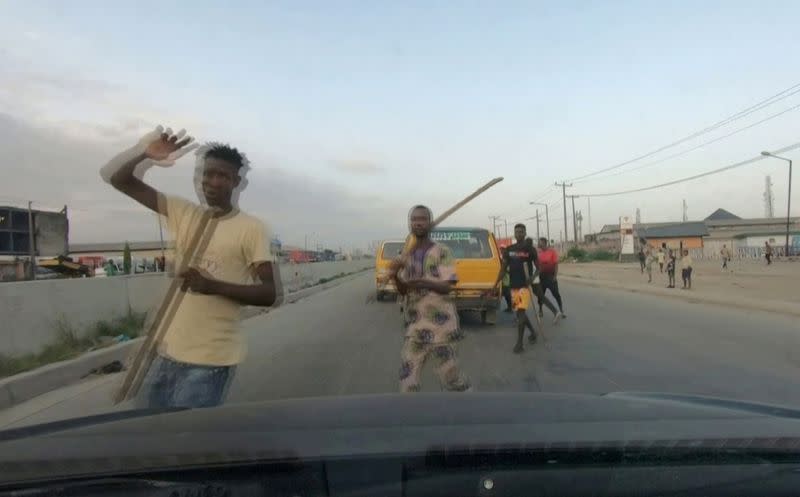 Men carry sticks and block a road in Lagos
