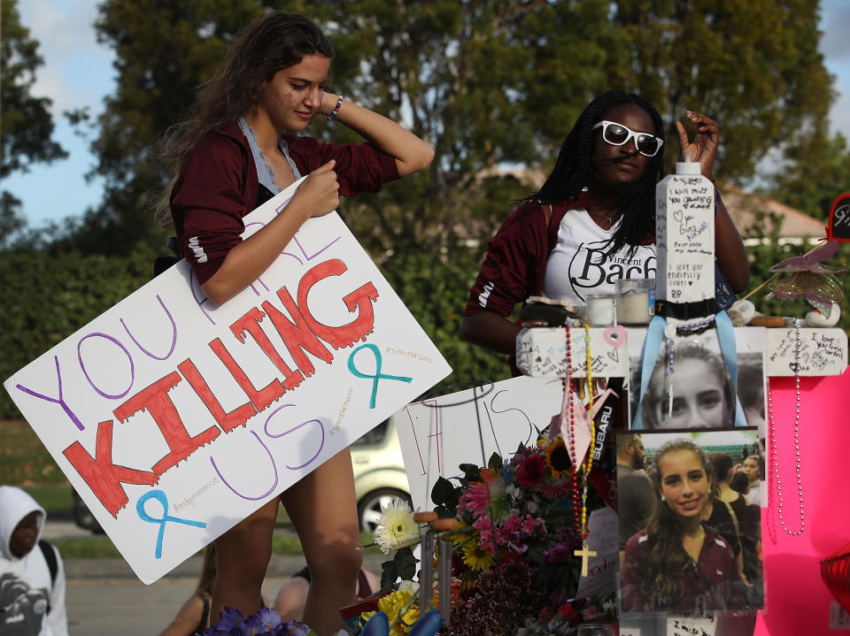 <p>Haleigh Grose, a 9th grader at Marjory Stoneman Douglas High School, holds a sign that reads, ‘You are Killing Us,’ as she visits the memorial setup in front of the school where 17 people that were killed on February 14, on February 21, 2018 in Parkland, Fla. (Photo: Joe Raedle/Getty Images) </p>