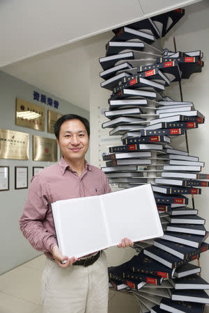 Scientist He Jiankui poses with "The Human Genome", a book he edited, for a photo at his company Direct Genomics in Shenzhen, Guangdong province, China August 4, 2016. REUTERS/Stringer