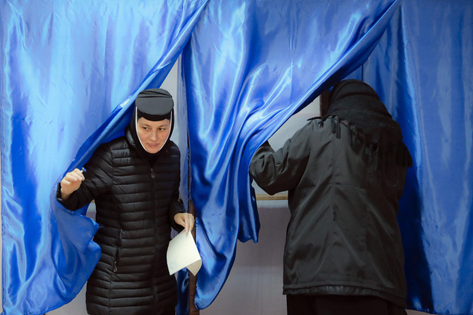 An Orthodox nun exits a voting cabin in Pasarea, Romania, Sunday, Nov. 24, 2019. Romanians are voting in a presidential runoff election in which incumbent Klaus Iohannis is vying for a second term, facing Social Democratic Party leader Viorica Dancila, a former prime minister, in Sunday's vote. (AP Photo/Vadim Ghirda)