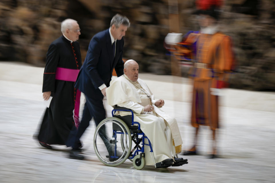 Pope Francis is helped in a wheelchair to meet the faithful during his weekly general audience in the Pope Paul VI hall at the Vatican, Wednesday, Jan. 24, 2024. (AP Photo/Andrew Medichini)