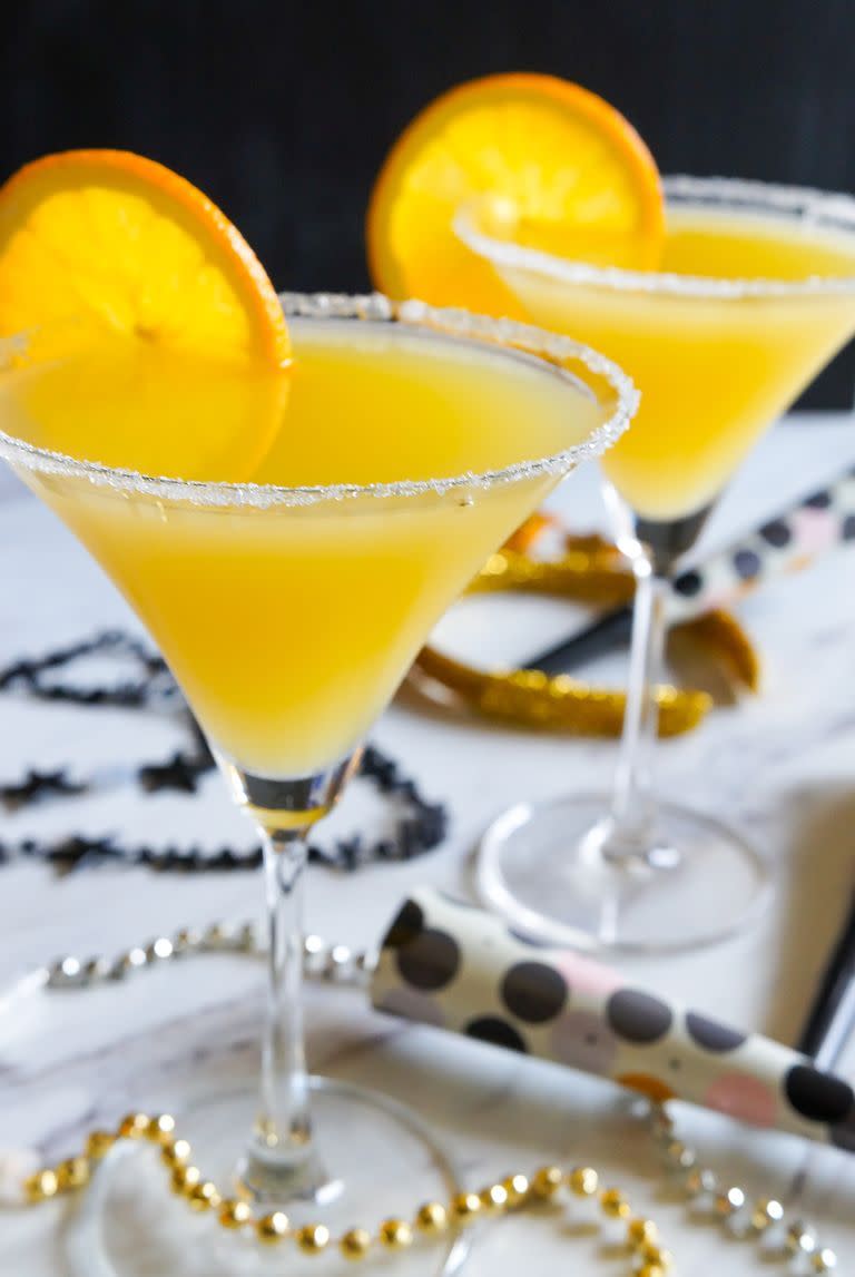 elderflower and orange cocktails in 2 martini glasses with decorations and orange wedges