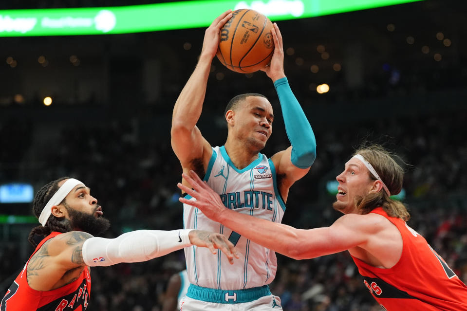 Charlotte Hornets guard Bryce McGowens, center, controls the ball while under pressure from Toronto Raptors guard Gary Trent Jr. , left, and forward Kelly Olynyk, right, during first-half NBA basketball game action in Toronto, Sunday, March 3, 2024. (Frank Gunn/The Canadian Press via AP)