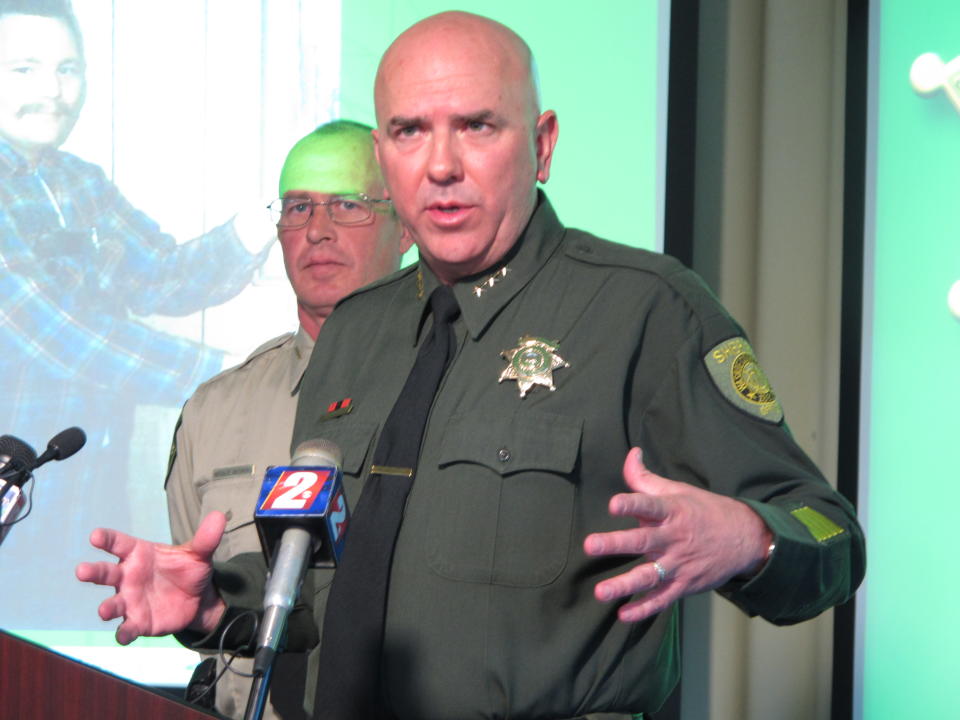 Washoe County Undersheriff Tim Kuzanek announces the opening of an investigation into the apparent 1980 homicide of George Benson Webster of Sun Valley, who is pictured in the background, Thursday, May 1, 2o14 in Reno, Nev. The highly decorated Vietnam veteran had been missing since then. His remains were found last summer in a septic tank at a home on the edge of the historic Comtock mining town of Virginia City about 20 miles from Reno. Detectives traced his identity with the help of a partial serial number on a medallion with the remains. (AP Photo/Scott Sonner)