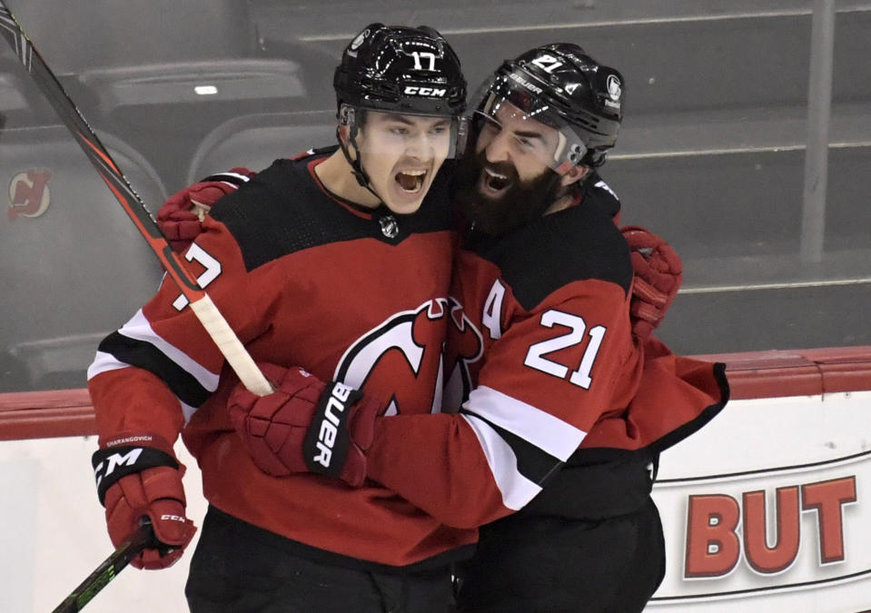 New Jersey Devils center Yegor Sharangovich (17) celebrates his game-winning overtime goal with right wing Kyle Palmieri (21) as the Devis defeated the Boston Bruins 2-1 in an NHL hockey game Saturday, Jan. 16, 2021, in Newark, N.J. (AP Photo/Bill Kostroun)