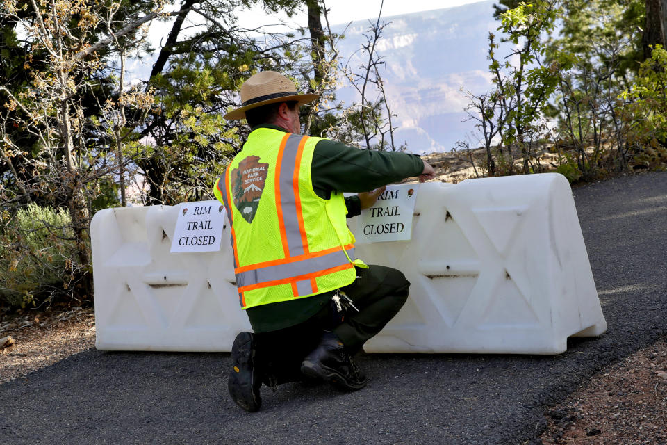 A Park Ranger blocks off a trail along Rim Drive at the Grand Canyon Friday, May 15, 2020, in Grand Canyon, Ariz. Tourists are once again roaming portions of Grand Canyon National Park when it partially reopened Friday morning, despite objections that the action could exacerbate the coronavirus pandemic.(AP Photo/Matt York)
