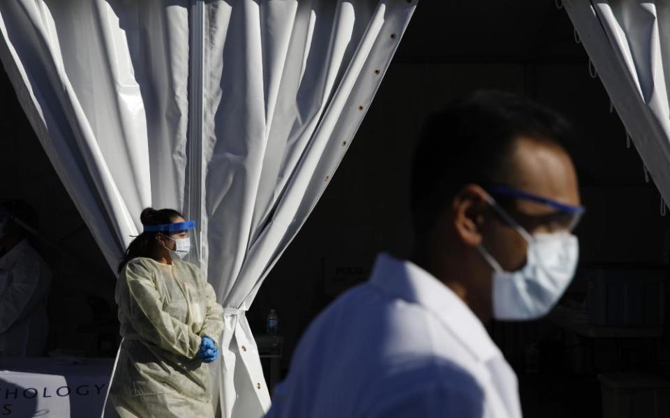 Healthcare workers with the University of Nevada Las Vegas School of Medicine wait in personal protective equipment for patients at a drive-thru coronavirus testing site on 24 March.