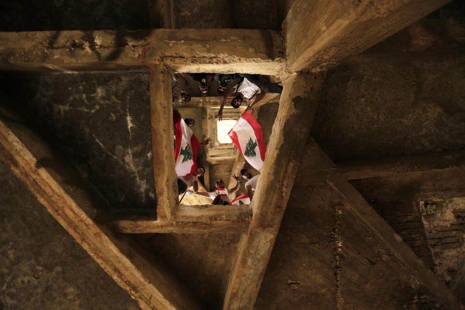 Anti-government protesters wave Lebanese national flag as they pose for photograph during a protest in Beirut, Lebanon, Sunday, Oct. 20, 2019. Thousands of people are gathering in downtown Beirut as Lebanon is expected to witness the largest protests on the fourth day of anti-government demonstrations. (AP Photo/Hassan Ammar)