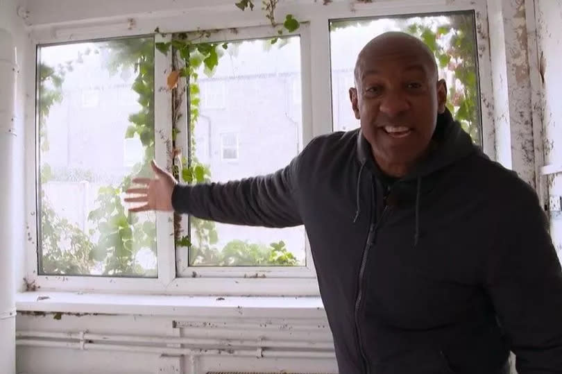 Homes Under The Hammer north Wales Dion Dublin presenter next to a window being attached by ivy