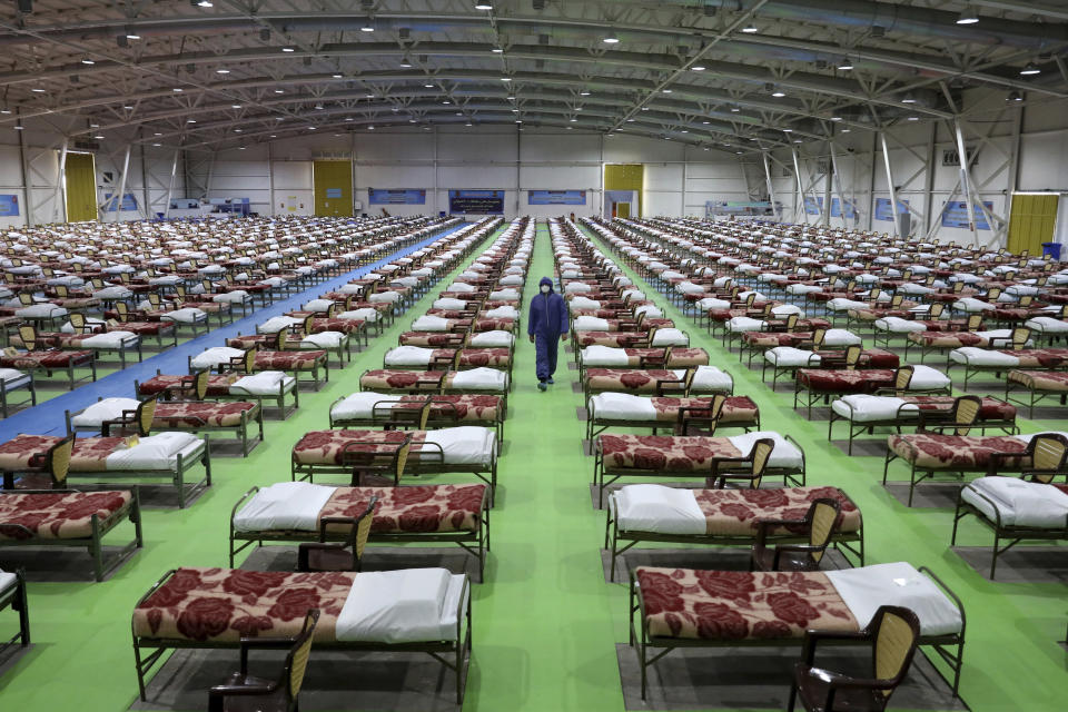 A member of the Iranian army walks past rows of beds at a temporary 2,000-bed hospital for COVID-19 coronavirus patients set up by the army at the international exhibition center in northern Tehran, Iran, on Thursday, March 26, 2020. (AP Photo/Ebrahim Noroozi)