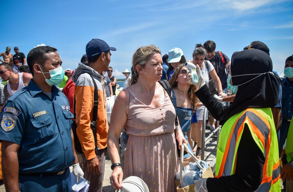 Indonesian health officials check body temperature of a foreign tourists arriving from Bali island heading to tourist area Gili Trawangan at the Bangsal port in Pemenang Lombok island on February 12, 2020. - The COVID-19 coronavirus that emerged in central China at the end of last year has now killed more than 1,100 people and spread around the world. (Photo by MOH EL SASAKY / AFP) (Photo by MOH EL SASAKY/AFP via Getty Images)