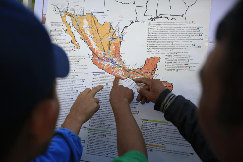 Migrants discuss their journey using a map posted inside the sports complex where thousands of migrants have been camped out for several days in Mexico City, Friday, Nov. 9, 2018. About 500 Central American migrants headed out of Mexico City on Friday to embark on the longest and most dangerous leg of their journey to the U.S. border, while thousands more were waiting one day more at a massive improvised shelter.(AP Photo/Rebecca Blackwell)