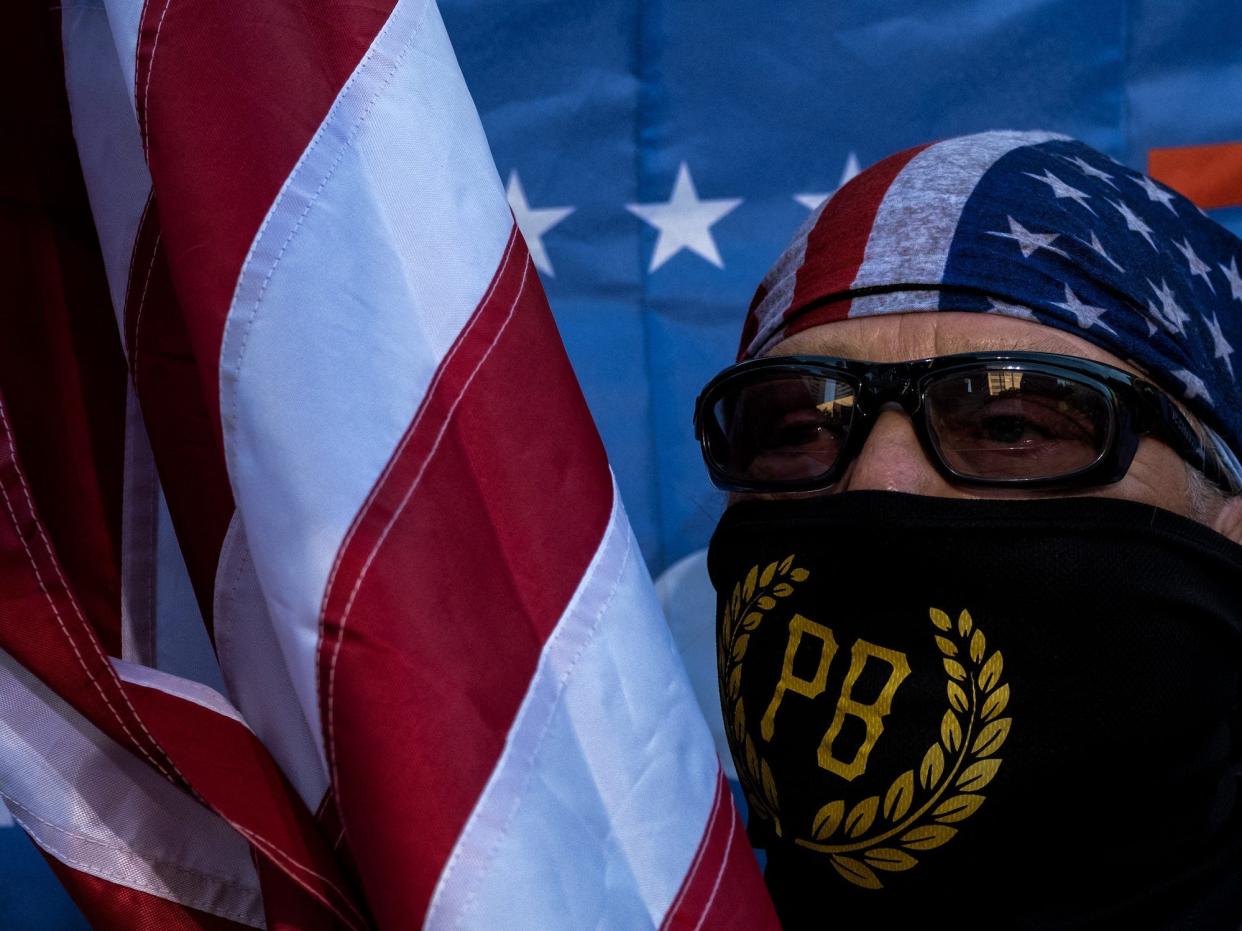 A member of the Proud Boys holds an US natioanl flag during a rally against gender-affirming care by Vanderbilt University Medical Center, at the War Memorial Plaza in Nashville, Tennessee, on October 21, 2022.