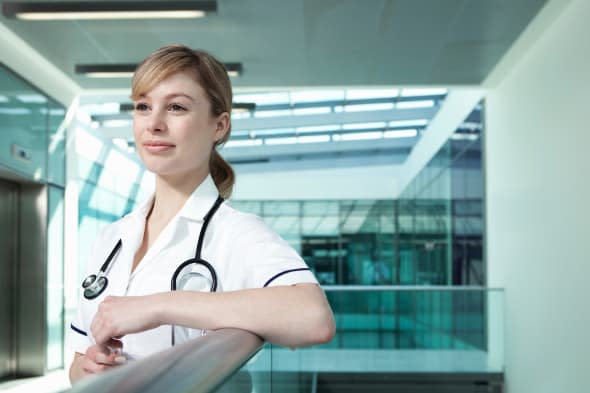 Portrait of nurse leaning on railing