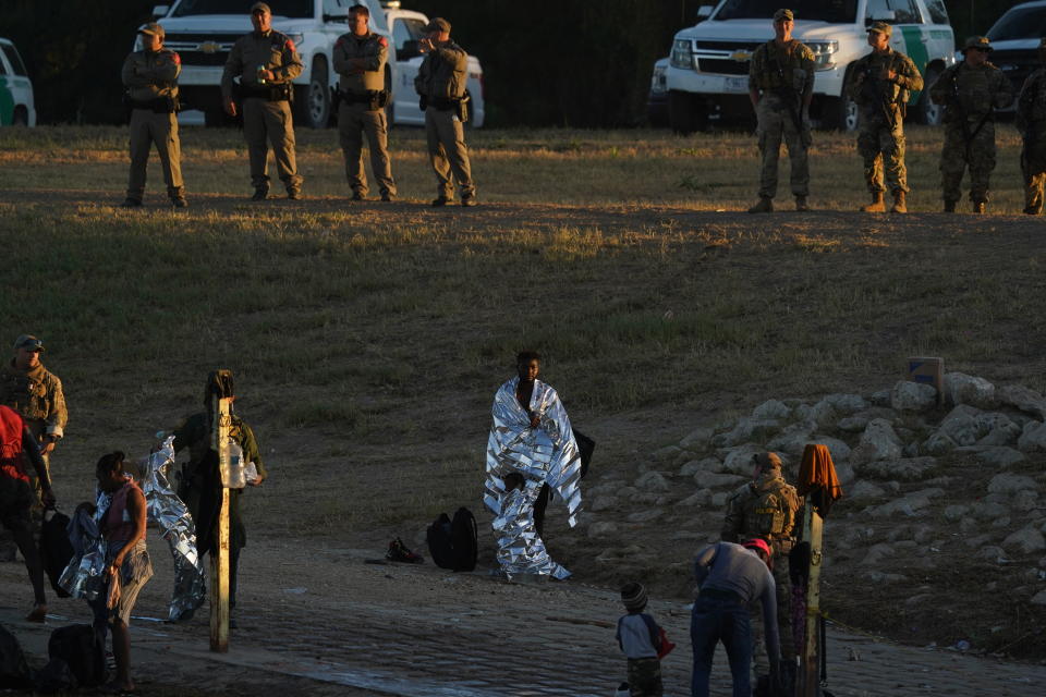 A migrant man and little boy stand wrapped in emergency blankets on the U.S. side of the Rio Grande river after they crossed the border to Del Rio, Texas, from Ciudad Acuna, Mexico, early Thursday, Sept. 23, 2021. (AP Photo/Fernando Llano)