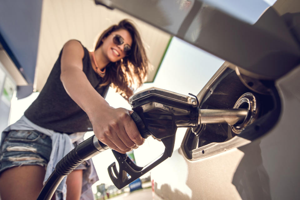 Close up of a woman refueling her car at fuel pump.