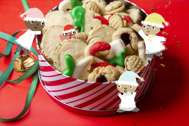 holiday cookies in a striped container with ribbons on a red surface