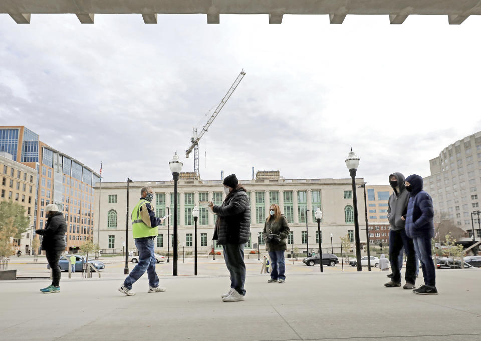 Voters participating in the first day of Wisconsin's in-person absentee voting window for the Nov. 3 election wait in line outside the city's City-County Building in Madison, Wis., Tuesday, Oct. 20, 2020. (John Hart/Wisconsin State Journal via AP)