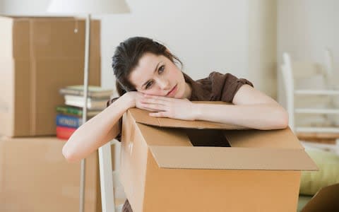 A woman resting on her moving box - Credit:  Tetra images RF