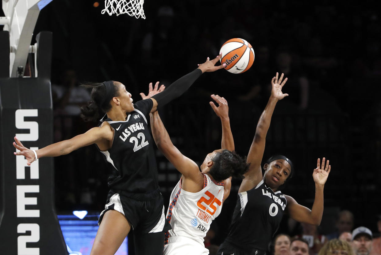 Connecticut Sun forward Alyssa Thomas (25) is fouled as she tries to shoot between Las Vegas Aces center A'ja Wilson (22) and guard Jackie Young (0) during the first half of a WNBA basketball game Sunday, Sept. 15, 2024, in Las Vegas. (Steve Marcus/Las Vegas Sun via AP)