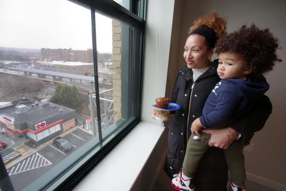 Juceila Cardoso and her 1-year-old son Sony Almeida take in the view out the window of a 7th floor apartment in the "Furniture Building" at 93 Centre St. during a tour of the refurbished building in downtown Brockton on Tuesday, March 26, 2024.