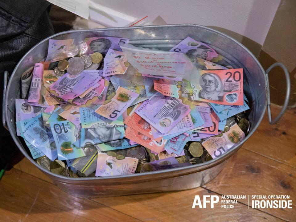 A top-down view over a metal bucket filled with cash, in an Australian police handout photo.