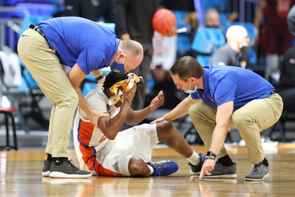 INDIANAPOLIS, INDIANA - MARCH 19: Tyree Appleby #22 of the Florida Gators sits injured on the ground as he is tended to by head coach Mike White (R) of the Florida Gators in the second half against the Virginia Tech Hokies in the first round game of the 2021 NCAA Men's Basketball Tournament at Hinkle Fieldhouse on March 19, 2021 in Indianapolis, Indiana. (Photo by Andy Lyons/Getty Images)