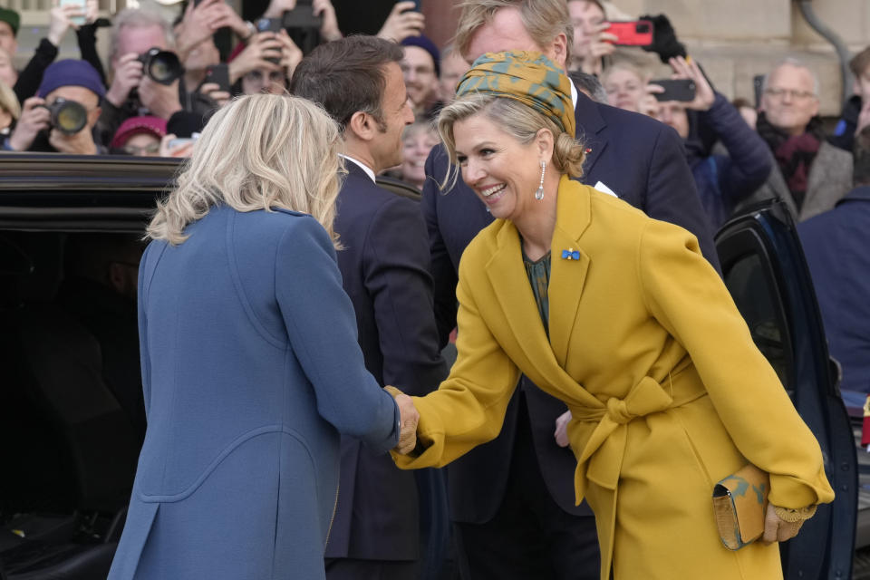 French President Emmanuel Macron's wife Brigitte Macron is welcomed by Dutch Queen Maxima, right, outside the royal palace on Dam square in Amsterdam, Netherlands, Tuesday, April 11, 2023. French President Emmanuel Macron begins a two-day state visit to the Netherlands on Tuesday and is making a speech on his vision for the future of Europe. (AP Photo/Peter Dejong)